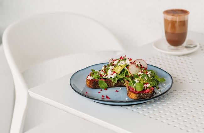 Avocado on toast sitting on a white table against a white wall.