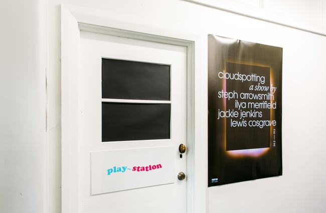 The door leading to play_station gallery with a giant poster next to it.