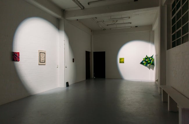 Artworks on two walls with spotlights focusing on both.