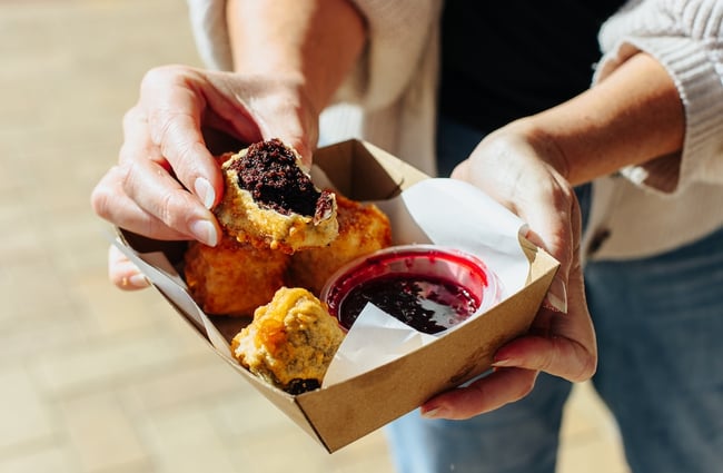 Close up of the cross section of a deep fried brownie bite with berry sauce.