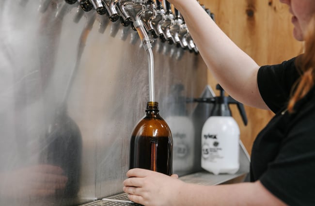 Woman pouring a beer at taps.