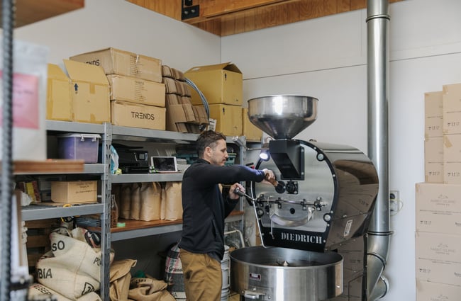 A man roasting coffee on a large machine.