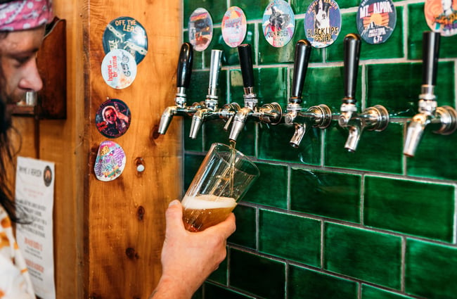 Close up of a man pouring a beer from the taps at Rhyme and Reason, Wānaka.