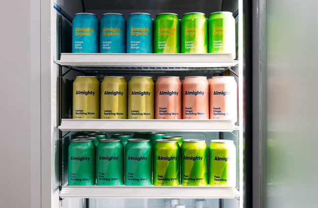 A close up of Almighty juices in cans in a fridge.