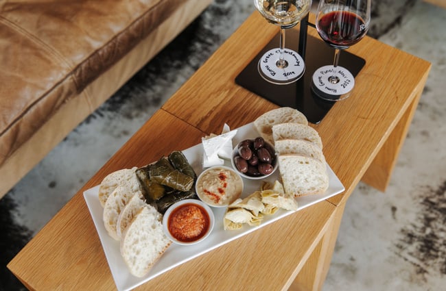A food platter on a low table next to a glass of red wine.
