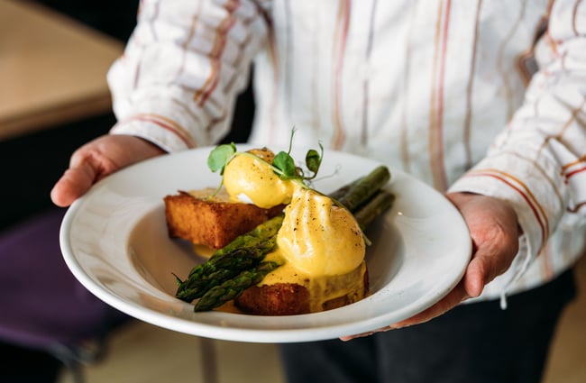 Waiter holding a plate of eggs benedict