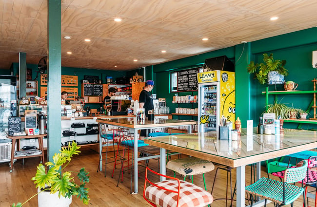 Eclectic and colourful cafe interior with mismatched chairs, plants and coffee on shelf