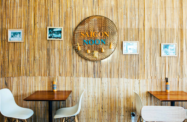 Two tables inside with Saigon Noon sign on the wall.
