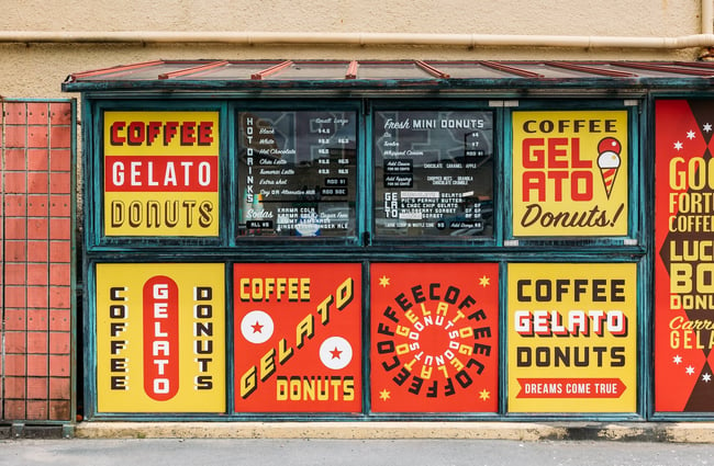 Retro 'Coffee Gelato Donuts' wording in red, yellow, black and white cover the downstairs glazed kiosk at Seashore Cabaret.