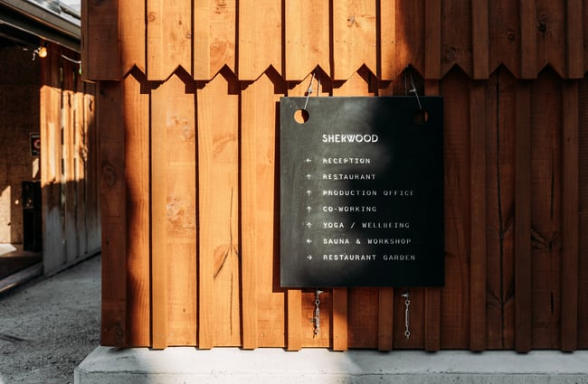 A black sign on a wooden wall.