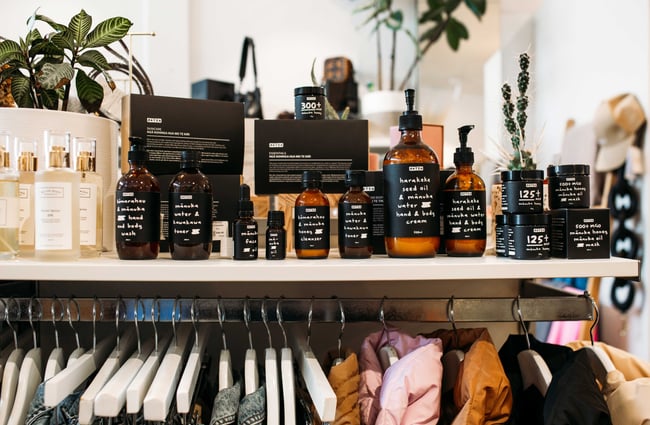 Aotea skincare products in brown bottles sitting on a white shelf over a rail of clothing at Sisters on London.