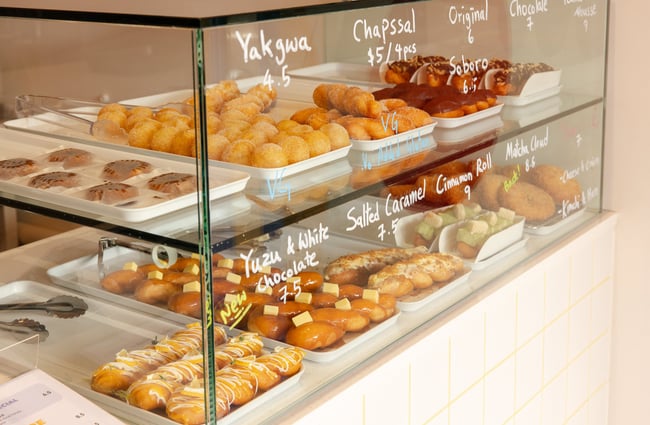 A close up of baked goods and pastries in a glass cabinet.