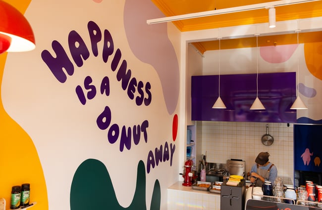 A painted sign that says 'Happiness is a Donut Day' on a wall.