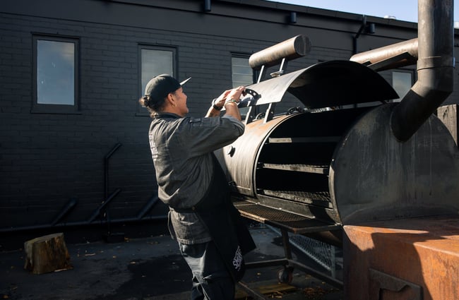 A man closing the lid of a smoker.