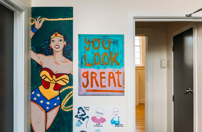 A painted sign that says 'you look great' on a wall next to an image of Wonder Woman.