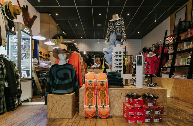 Skateboards and mannequins wearing clothes on display in the middle of the store.