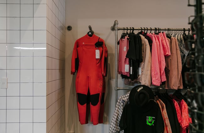 A close up of pink clothes and a wet suit on hangers inside Soul Surf and Skate.
