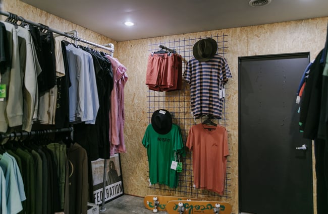Men's t-shirts and hats on a wall.