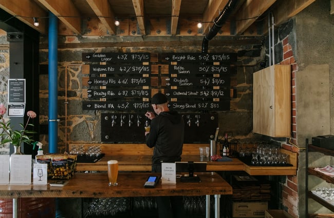Person standing behind the bar with all the beer taps on show at Steamer Basin, Dunedin.