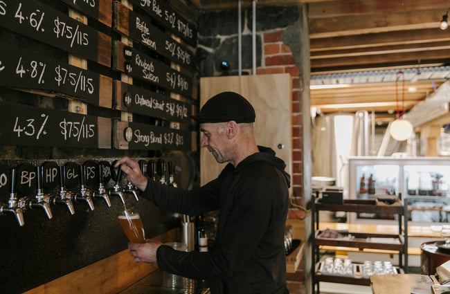 A man pouring a beer behind the bar at Steamer Basin.