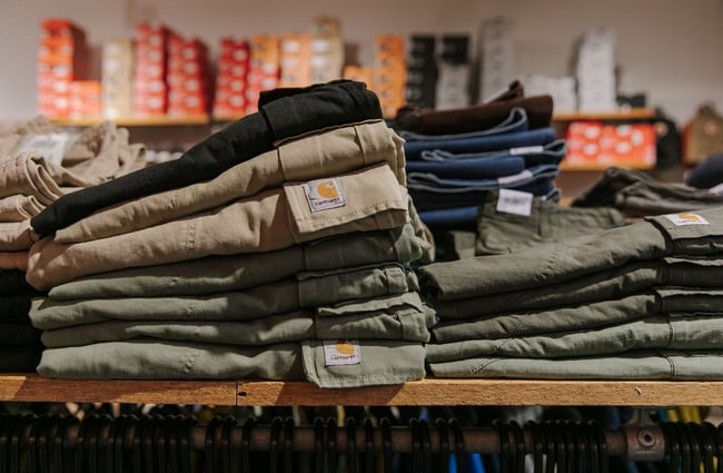 Folded piles of Carhartt cargo pants at Stencil.