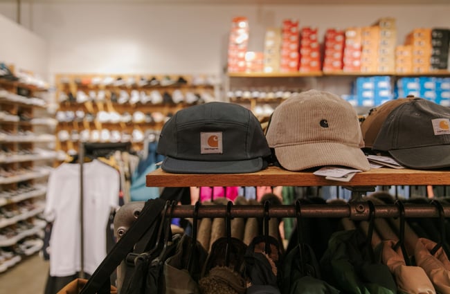 Carhartt caps sitting on the wooden top of clothing racks at Stencil.