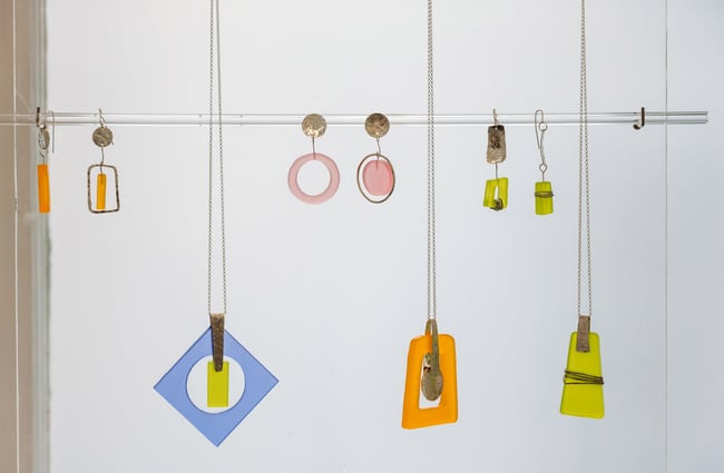 Colourful necklaces hanging up in a gallery.