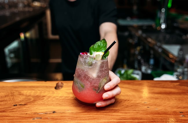 A hand holding a pink cocktail.