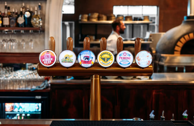 Beer stickers on taps at a bar.