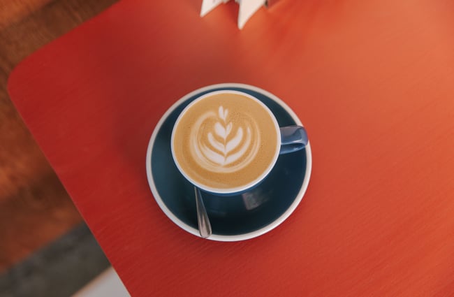 A close up of a flat white on a red table.