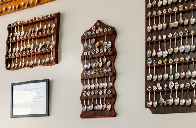 Vintage spoons lined up in rows on a wall.