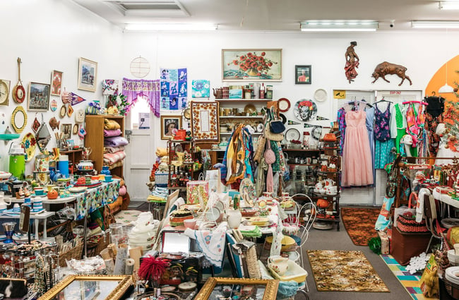 Busy vintage shop interior filled with retro furniture, fashion and homewares