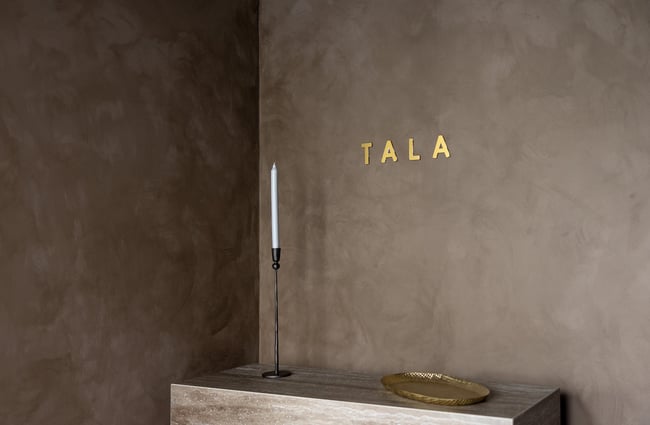 A gold 'Tala' sign on a wall.
