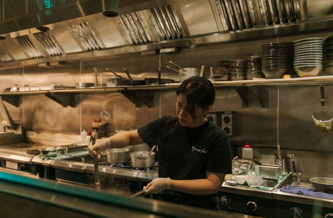 A female chef wearing black in a restaurant.