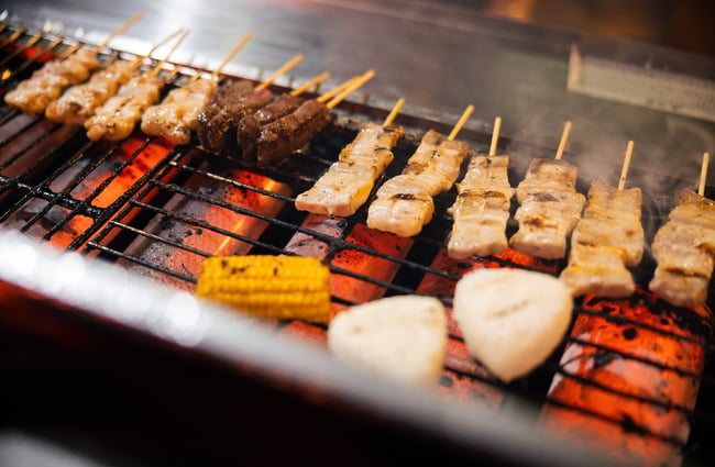 A close up of skewers being cooked on an open grill.