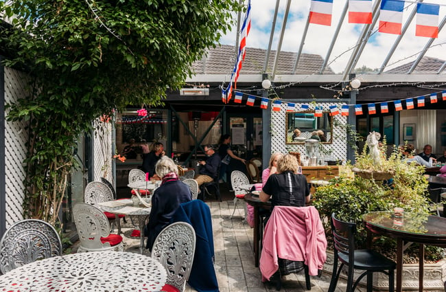 Outdoor area of Tartines in Lower Hutt with people dining underneath bunting of French flags