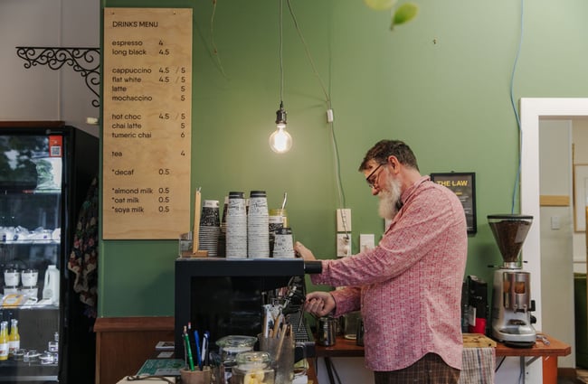 A barista in a patterned shirt making a coffee.
