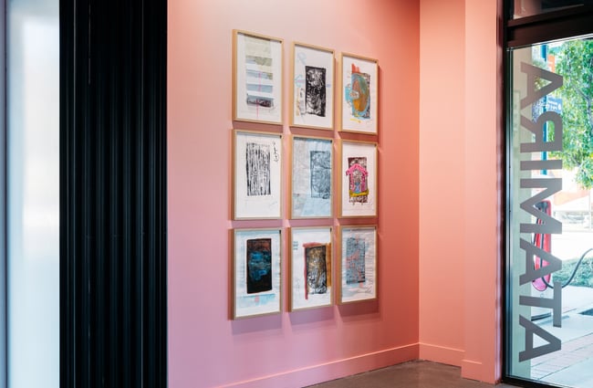 Framed works of art on a pink wall.