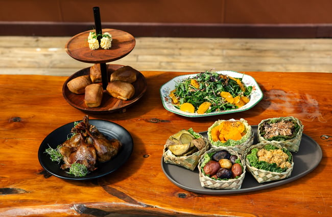 Plates of Maori food on a black table.