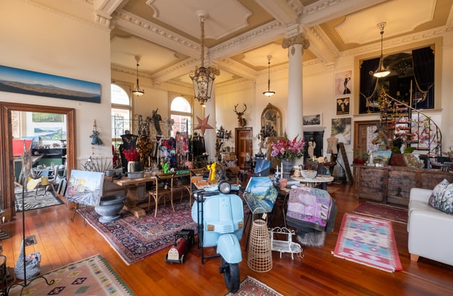 Interior of shop with ornate ceilings and colonial pillars, surrounded by a busy array of vintage pieces