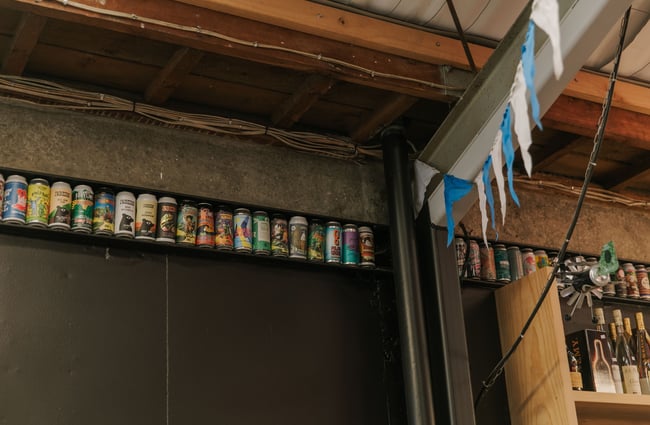Beer cans on display at the top of a wall.