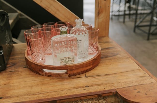 A gin bottle and crystal glasses on a round tray.