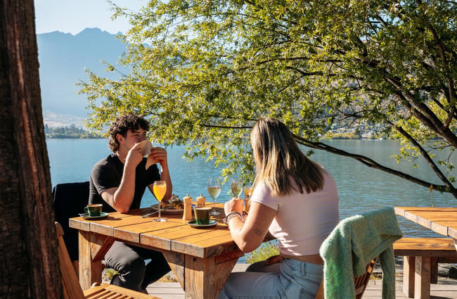 A man and woman eating by the lake at Boat Shed.