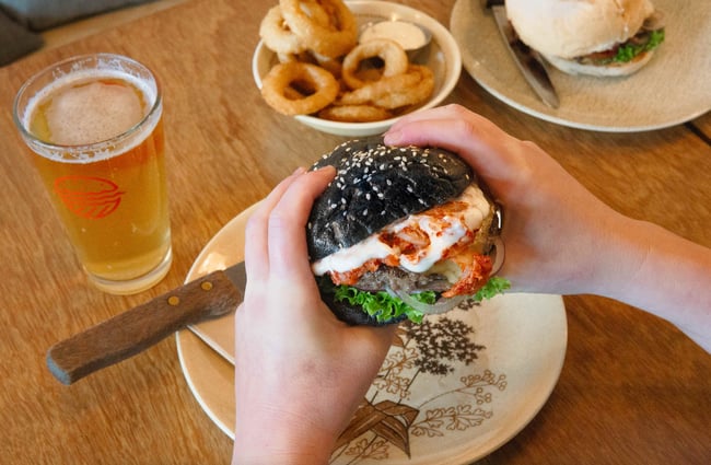 Hands holding on to a burger.