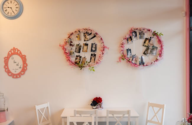 Pink wreaths on a wall above tables and chairs.