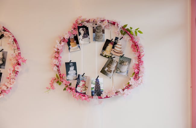 Pictures of cakes inside a pink wreath on a wall.