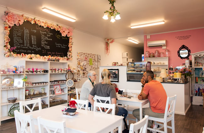 Customers dining inside a pretty and pink cafe.