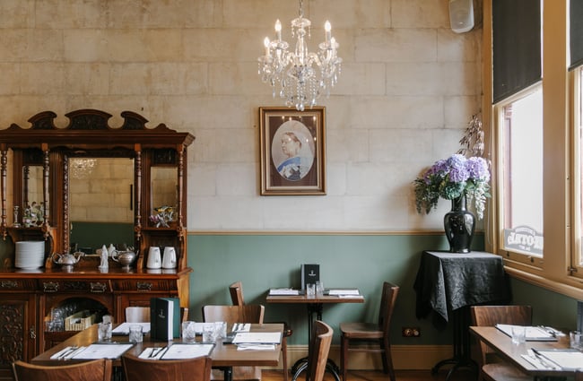 The inside of a dining room at The Criterion with a portrait of Queen Victoria on the wall.
