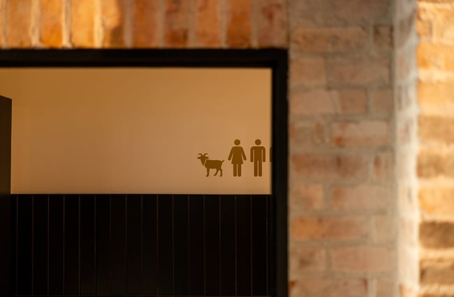 A toilet sign of a man, woman and goat sign.
