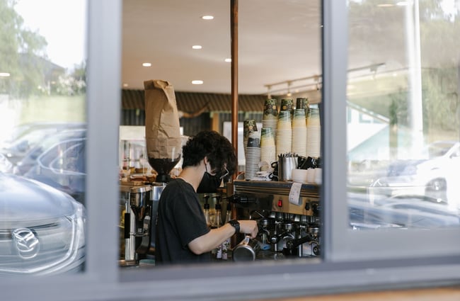 Looking at a staff member through a window making coffee at the Greedy Cow Café in Tekapo.